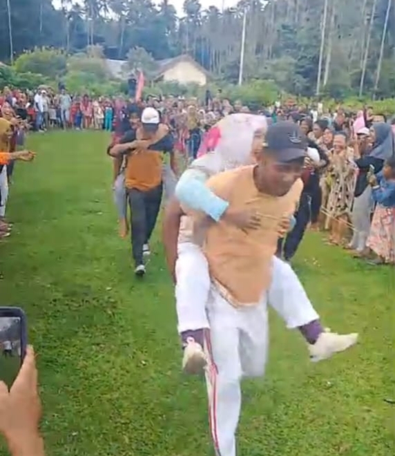 Foto: Lomba Suami Gendong Istri di Lapangan Bola Desa Waikafia.